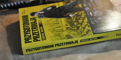 Książka "Przygotowani przetrwają. Survival miejski" leży obok noża. Podręcznik do przetrwania w miejskiej dżungli.