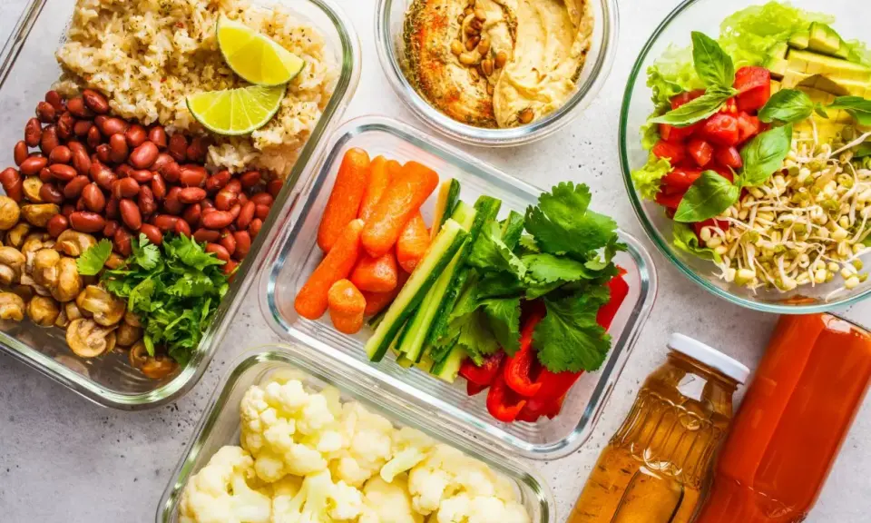 Gotowe pojemniki z jedzeniem na biwak bez gotowania: ryż z fasolą i pieczarkami, warzywa pokrojone w słupki, kalafior, sałatka z pomidorami i awokado, hummus i napoje.