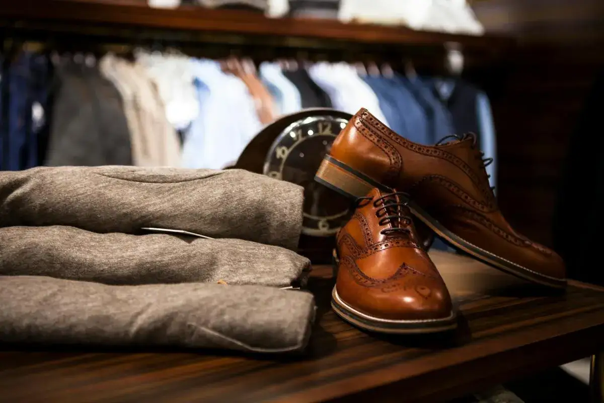 Eleganckie, brązowe skóra licowa buty typu oxford, ułożone obok szarych swetrów, gotowe na stylowe wyjście.